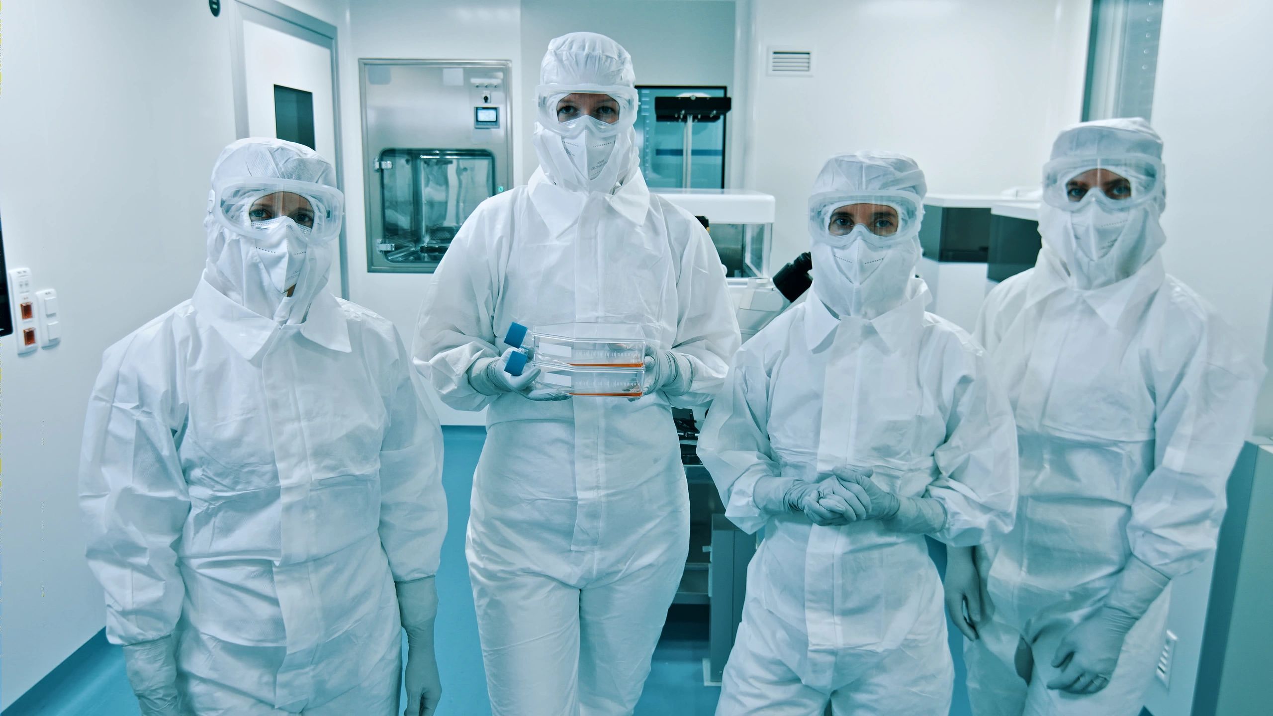 Medical professionals in protective gear in a sterile clinical setting